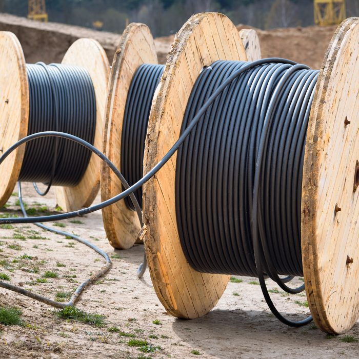 Concept of electricity supply for construction projects. Several wooden coils with power cable, laid in trench.