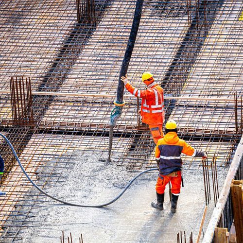 Workers pouring concrete. Concrete pouring on the construction site. Concrete pump. Reinforcement steel, reinforcing bar, rebar, foundation plate. Unrecognizable people
