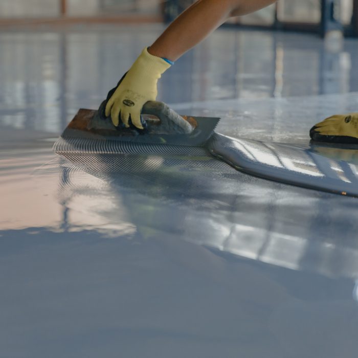 The worker applies gray epoxy resin to the new floor